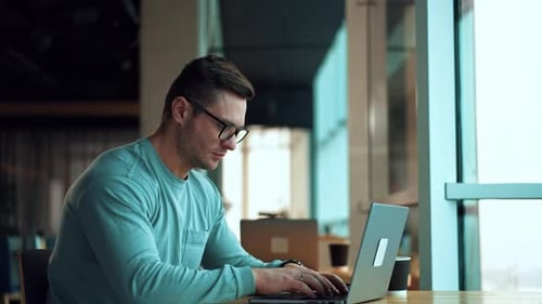 Man Working on Laptop in Open Office Environment