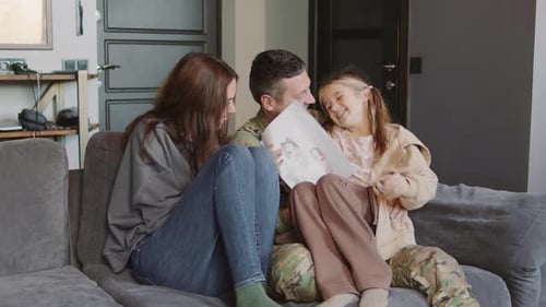 Family on Couch Looking at Child's Drawing