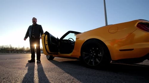 Man Next to a Yellow Convertible at Sunrise