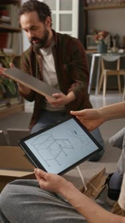 Femme tenant une tablette avec manuel d'assemblage de l'armoire et panneaux de vérification pour mari