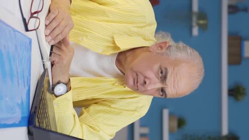 Vertical video of Home office worker old man looking at camera curious and confused.