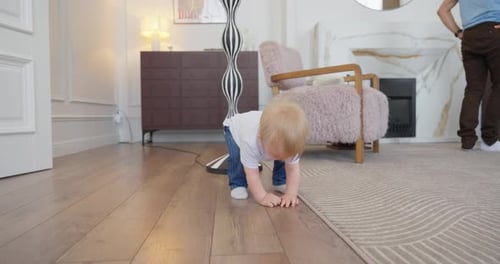 Blond Toddler Learning to Crawl and Walk Across a Cozy Modern Living Room While Parents Watch and