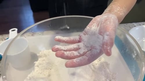 Close of up child's hands exploring flour. Baking has become a popular shelter in place activity dur