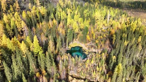 Small turquoise lake in an autumn mountain forest