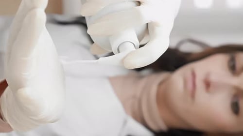 Eine professionelle Kosmetikerin hält Feuchtigkeits- und Hautpflegecreme zur Hand und trägt sie auf