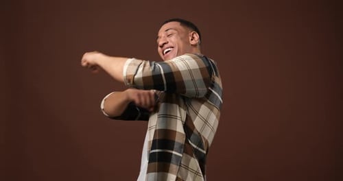 Happy Young African American Man Dancing Over Brown Studio Background