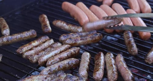 Brutzelnde Würstchen und Hotdogs auf einem Barbecue-Grill beim Sommer-Grillabend