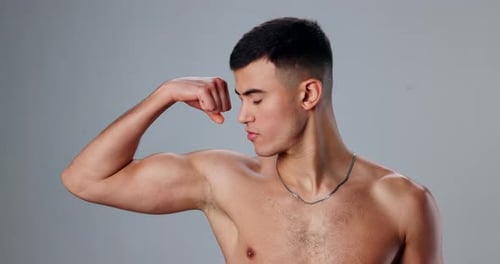 Face, flexing and man with training, bicep and wellness with bodybuilder on gray studio background
