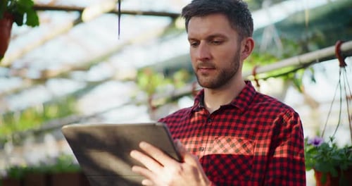Gardener Using Digital Tablet in Greenhouse