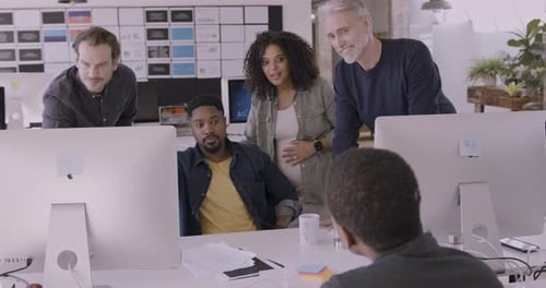 Group of Coworkers Meeting round a Desktop Computer in Discussion