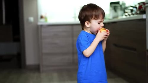 Cute Child Eats Red Apple in Kitchen