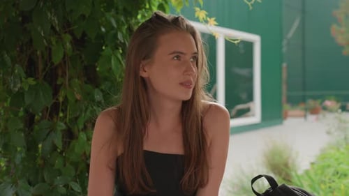 Young Woman Talking Outdoors near Green Building on Sunny Day