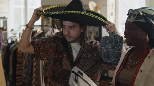 Laughing Diverse Couple Trying on Silly Vintage Hats at Second Hand Outlet