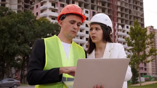 A Builder and an Architect with a Laptop are Standing at a Construction Site