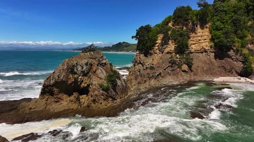 Epic Unspoilt jagged rocky outcrop along coastline—turquoise waves crash against cliffs, windswept t