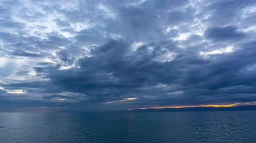 Dramatisch Wolken über ruhigem Meerwasser bei Sonnenuntergang