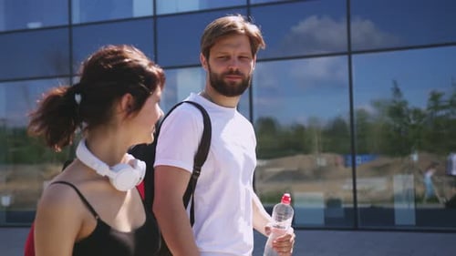 Handsome Man and Beautiful Woman Dressed in Sport Clothes Walking and Talking at Urban Area After