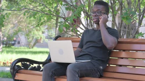 Young Adult Working on Laptop and Phone in Park