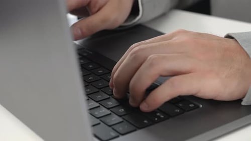 Unrecognizable businessman hands typing on a keyboard laptop computer at a desk in an office. Digita