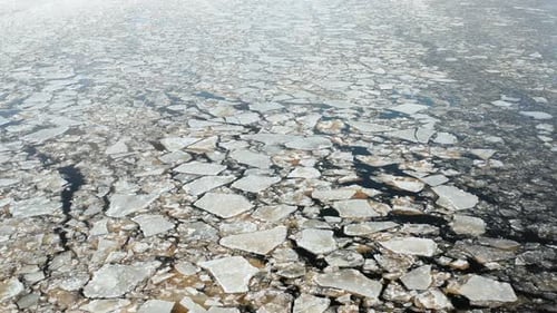 Wunderschöner Luftüberblick auf rissige Eisschollen, die im Meer schwimmen. Dunkler Wasserhintergrund. Forw