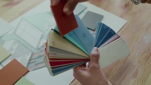 Primer plano de las manos de un diseñador que sostiene la guía de colores y los tonos a juego