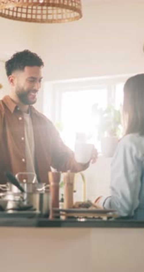 Man Sips Drink and Smiles at Woman in Kitchen