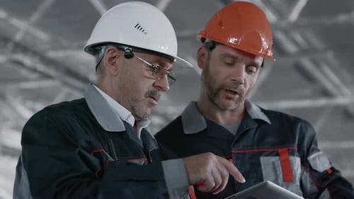 Construction Workers Reviewing Tablet Data on Building Site