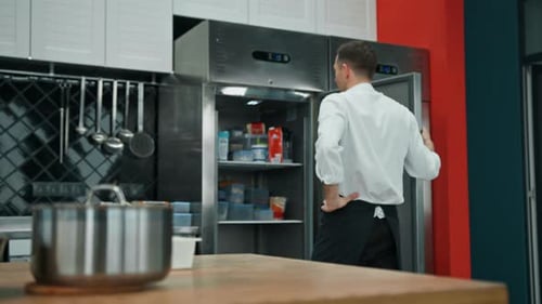 professional kitchen chef looks into the fridge and chooses ingredients for cooking food concept