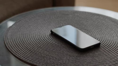 Hand Picking Up Cell Phone Device on Table