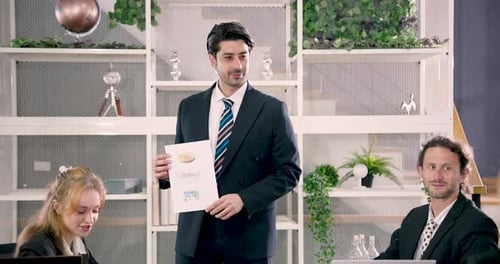 Male executive holding printed business report during office meeting while explaining chart and data