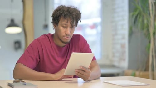 Young Adult Uses Tablet at Desk Indoors