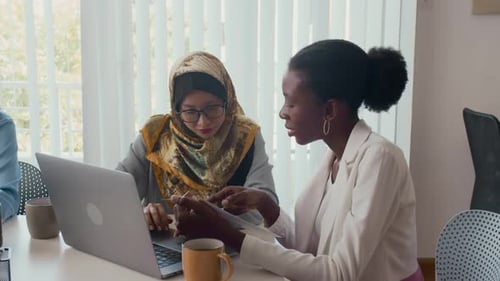 Two Young Women Working Together in Office