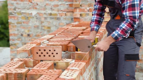 Construction Worker Building a Brick Wall Carefully