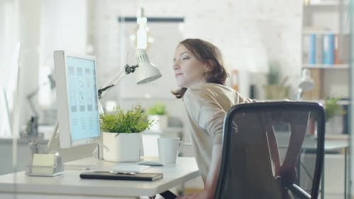 Woman Sits at Desk and Works at Computer