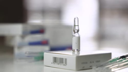 Medical Ampule Standing on Box with Syringes