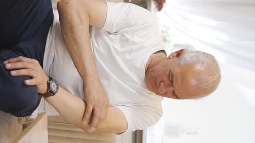 Vertical video of Old man with elbow pain.