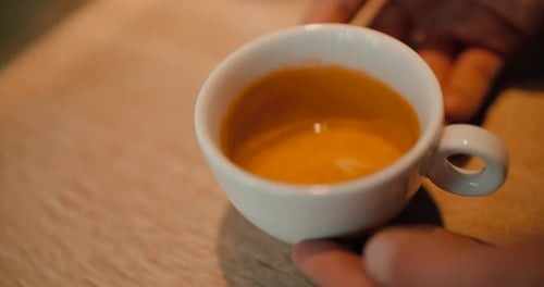 Slow motion of pouring milk into a cup of coffee on an old wooden table, top view