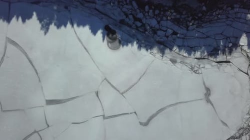 Aerial ascending view of big cracks during the thaw of a lake.