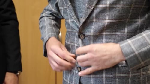 24 1Der Mann knöpft seine Jacke zu. Stylische Herrenbekleidung.