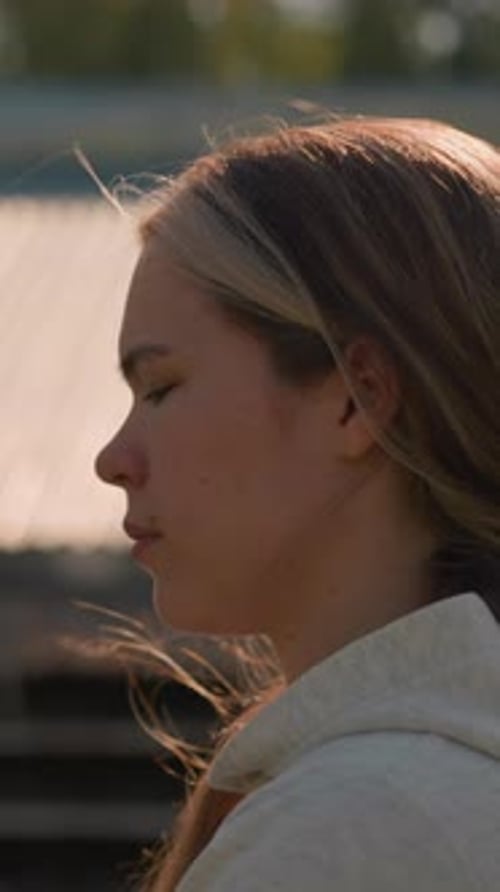 Reflective Woman Walking By Empty Stadium Bleachers in Thoughtful Mood