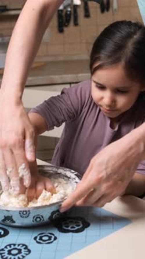 Girl Mixing Dough with Adult in Kitchen