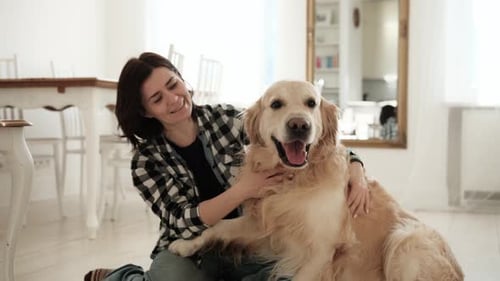 Woman Cuddling Golden Retriever Dog on Floor