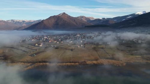 A Drone Flies Over a Mountain Village Covered in Morning Fog