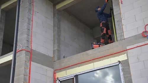 Worker Installs Electrical Wiring in New Building Under Construction in Urban Area