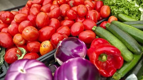 A variety of fresh colourful vegetables together on a market stall, dolly away.