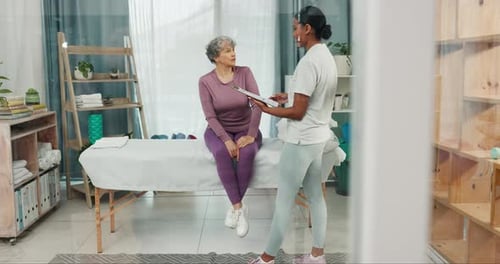 Patient talking to physiotherapist with clipboard in clinic for rehabilitation assessment