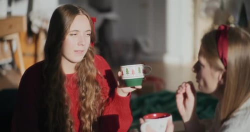 Mujer bonita con taza de café hablando con su hermana en Bright Home durante Navidad