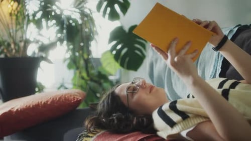Woman Reads Book on Couch Indoors Daytime