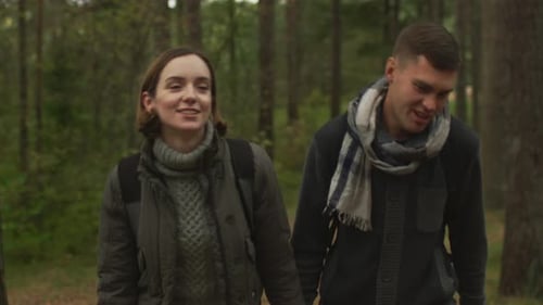 Couple walking in slow motion towards the camera in an autumn forest.