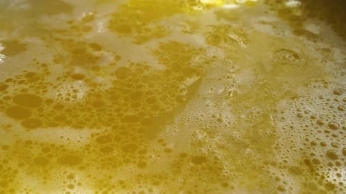 close up yellow boiling soup, foams in the boiling soup